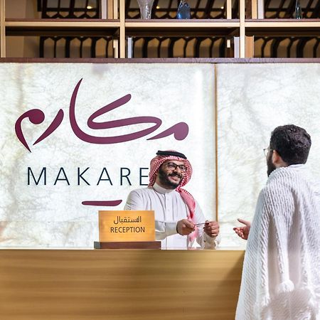 Makarem Ajyad Makkah Hotel Mecca Екстер'єр фото The photo depicts a reception area in a hotel or establishment named "Makarem." In the image, a receptionist, dressed in traditional attire, is smiling and interacting with a guest who is wearing a white robe, commonly known as a thobe or ihram. The 