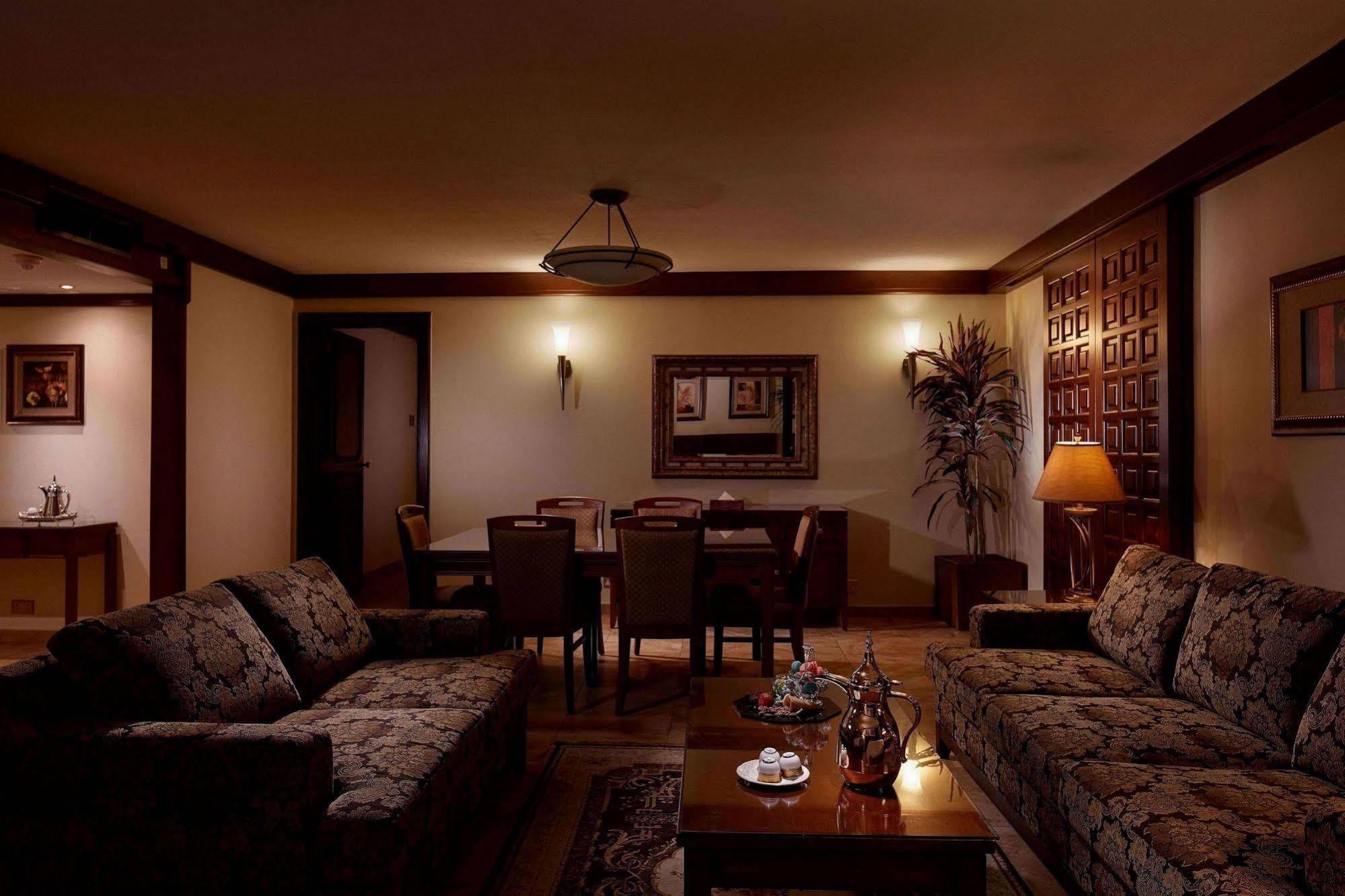 Makarem Ajyad Makkah Hotel Mecca Екстер'єр фото The photo depicts a cozy living room setting. It features two patterned sofas facing each other with a wooden coffee table in the center. The room is softly illuminated, creating a warm atmosphere. On the walls, there are decorative elements, includi