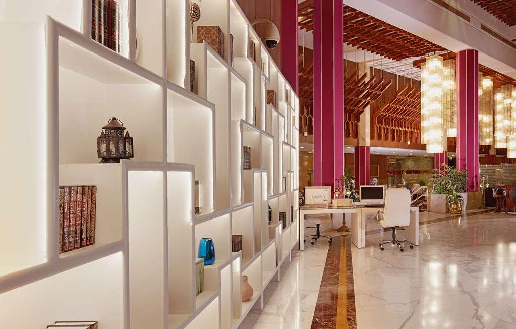 Makarem Ajyad Makkah Hotel Mecca Інтер'єр фото The photo shows a modern interior space, likely a lobby or lounge area of a stylish hotel or building. There is a partition wall made up of white shelving units illuminated from within, displaying various decorative items, books, and vases. The desig
