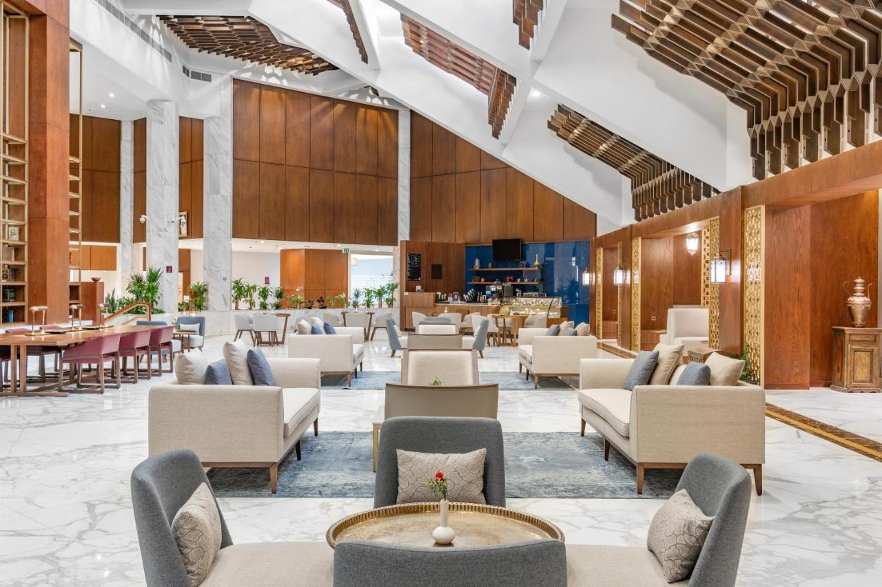 Makarem Ajyad Makkah Hotel Mecca Екстер'єр фото The photo depicts the interior of a modern and elegantly designed lobby or lounge area. It features a spacious layout with high ceilings, showcasing a combination of wooden elements and marble flooring. 

In the center, there are several seating arra