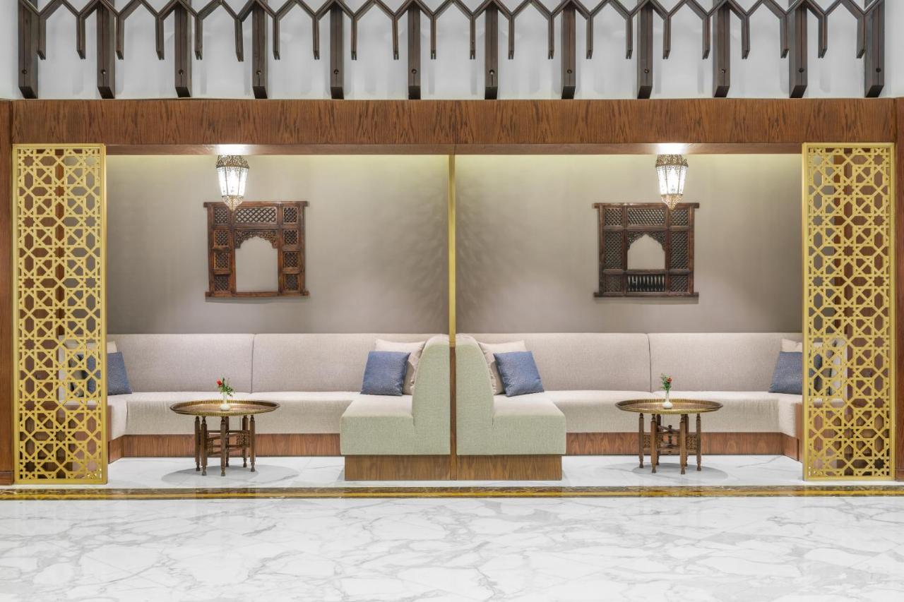 Makarem Ajyad Makkah Hotel Mecca Екстер'єр фото The photo depicts a modern, elegantly designed seating area. It features a pair of sofas with light-colored upholstery, accented by blue cushions. There are several small tables in front of the sofas, likely meant for drinks or decorative items. The 