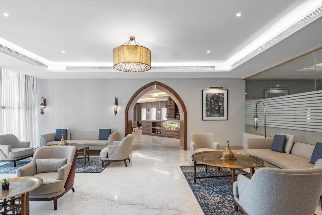 Makarem Ajyad Makkah Hotel Mecca Екстер'єр фото The photo shows a modern and elegantly designed lounge area. It features light-colored walls and marble flooring, complemented by stylish furniture including several armchairs and small tables. The lighting is soft, provided by a decorative chandelie