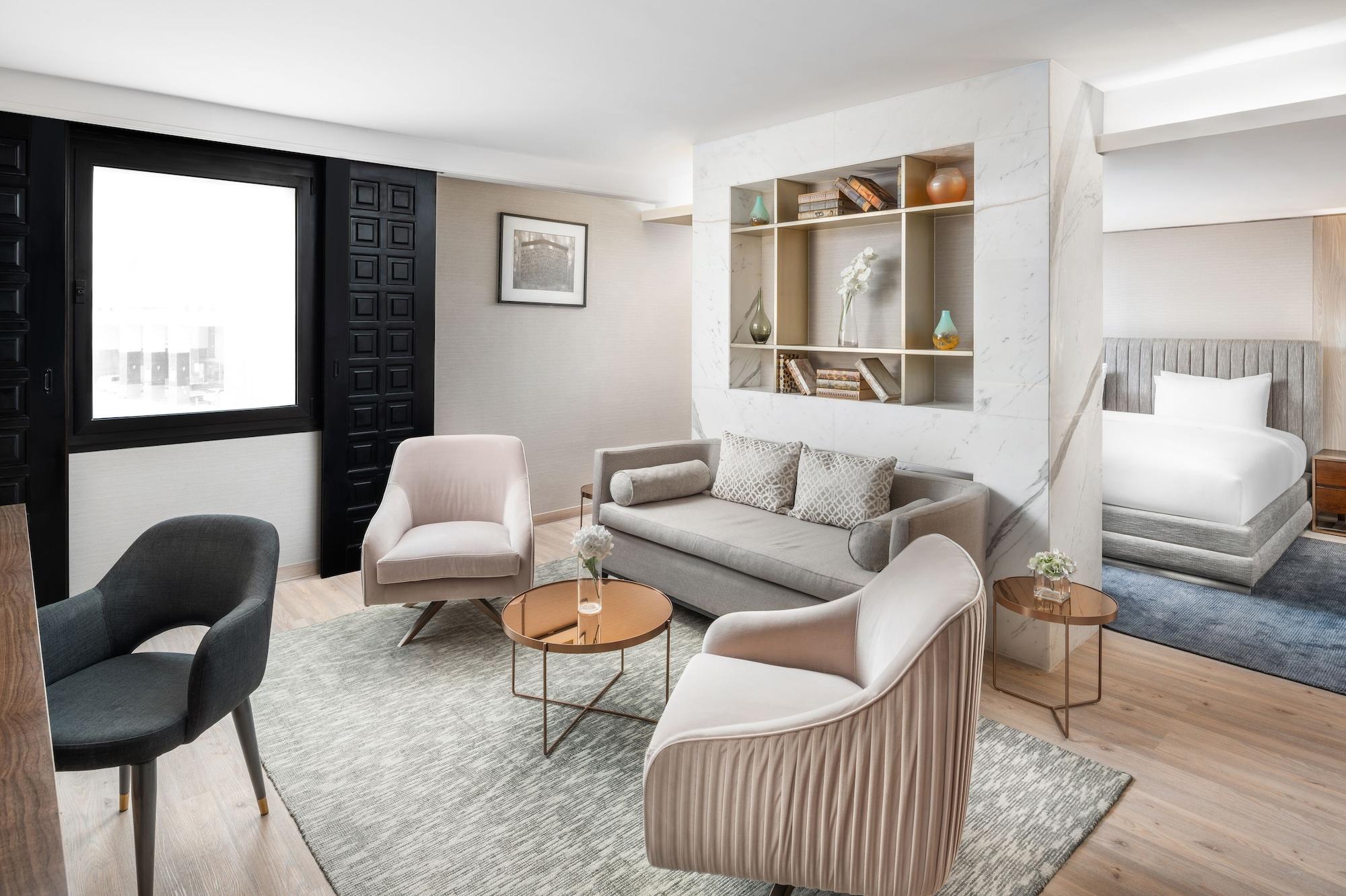 Makarem Ajyad Makkah Hotel Mecca Екстер'єр фото The photo shows a stylish and modern living space. There is a comfortable sofa in a neutral color, accompanied by two elegant armchairs and a small round table. The floor is wooden, adding warmth to the room. A decorative shelf in the background feat