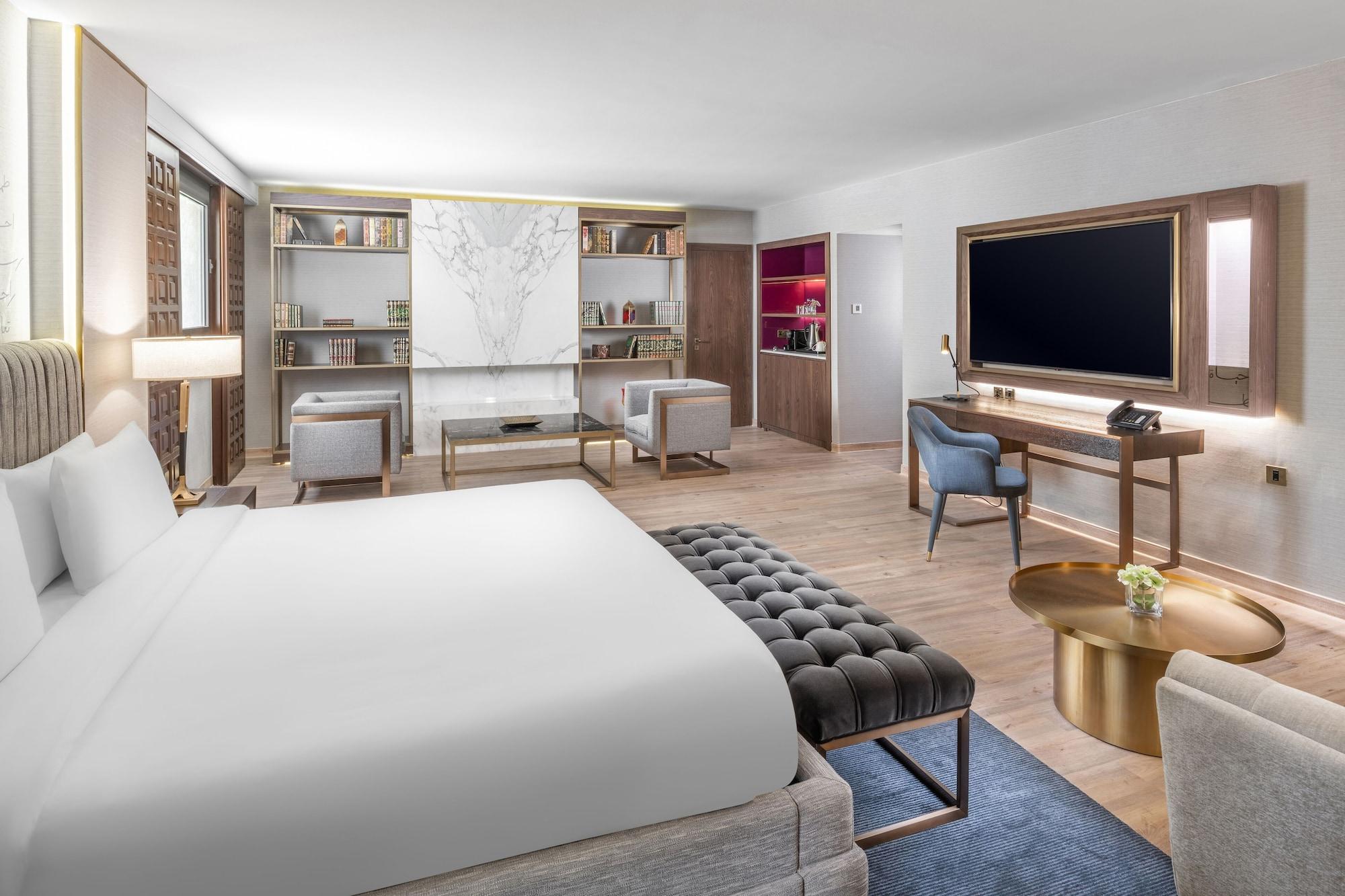 Makarem Ajyad Makkah Hotel Mecca Екстер'єр фото The photo shows a modern hotel room designed with a contemporary aesthetic. The room features a large bed with white bedding, complemented by a stylish tufted bench at the foot of the bed. To the side, there are two comfortable armchairs positioned a
