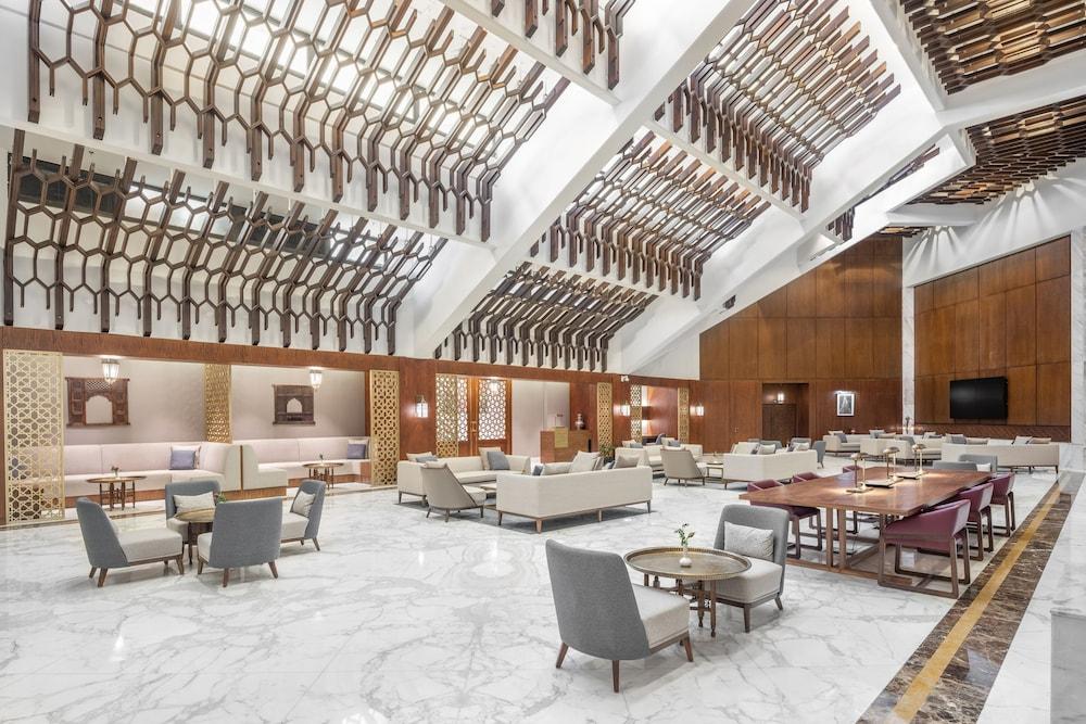 Makarem Ajyad Makkah Hotel Mecca Екстер'єр фото The photo shows a spacious and elegantly designed lobby area, likely within a hotel. The interior features high ceilings with a unique architectural design, showcasing wooden elements arranged in a geometric pattern. The flooring is a polished marble