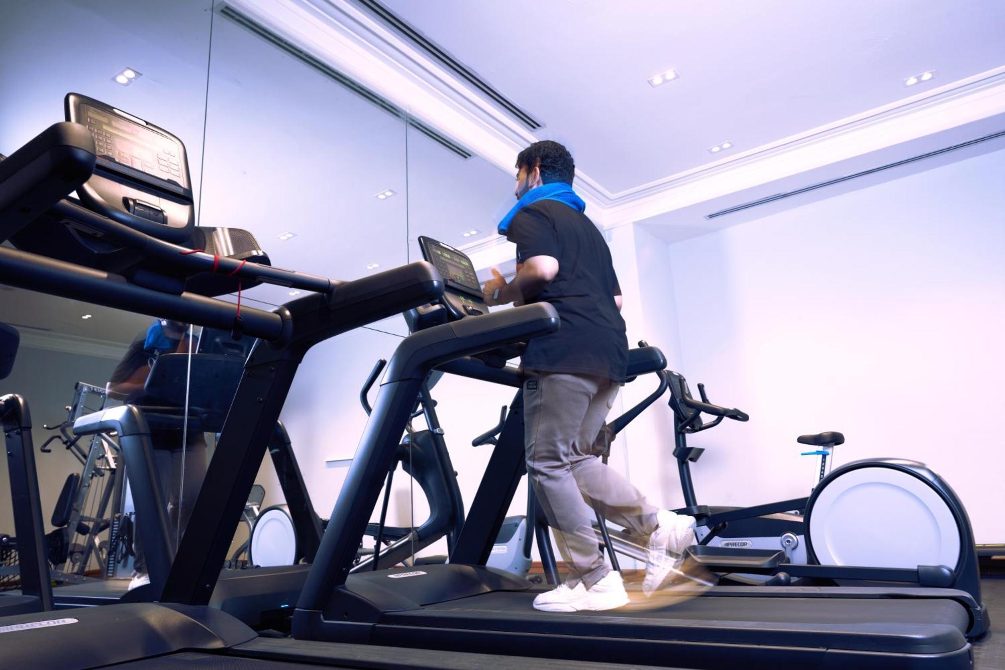 Makarem Ajyad Makkah Hotel Mecca Екстер'єр фото The photo shows a person exercising on a treadmill in a modern gym or fitness room. The individual is wearing a blue neck support while jogging on the treadmill, which is set against a backdrop of large mirrors. There are also additional exercise equ