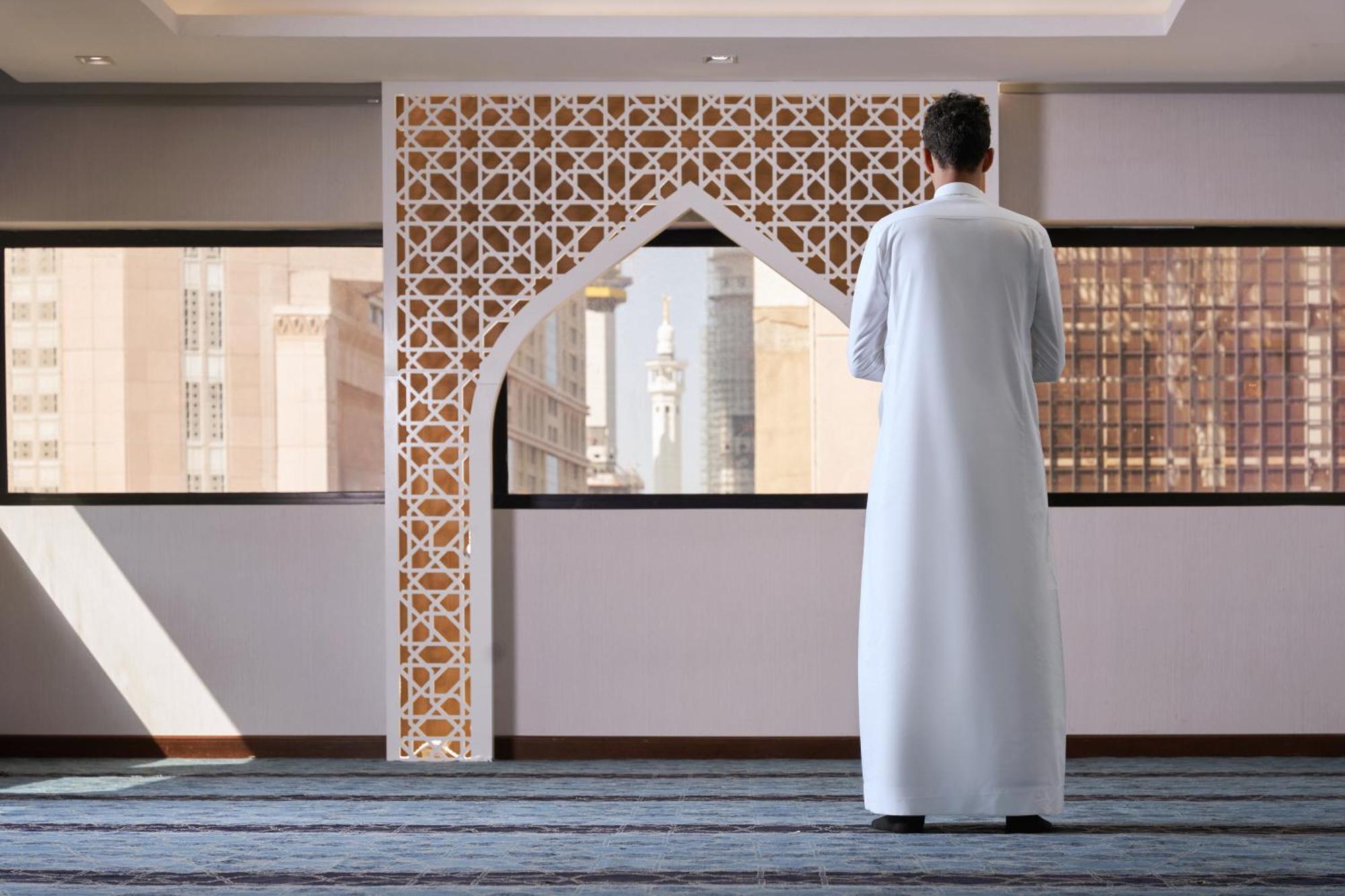 Makarem Ajyad Makkah Hotel Mecca Екстер'єр фото The photo depicts a person standing with their back facing the viewer, wearing a traditional white garment. They are in a spacious interior setting that features an ornate archway with intricate patterns, typical of Islamic architecture. Through the 