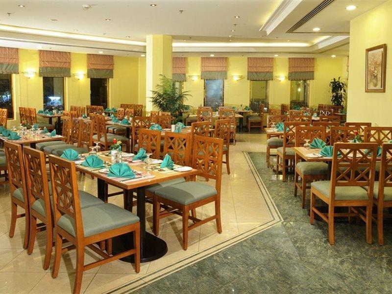 Makarem Ajyad Makkah Hotel Mecca Екстер'єр фото The photo shows an interior view of a restaurant. It features wooden tables and chairs arranged neatly throughout the space. Each table is set with turquoise napkins, contributing to the overall decor. The walls are painted a soft yellow, and there a