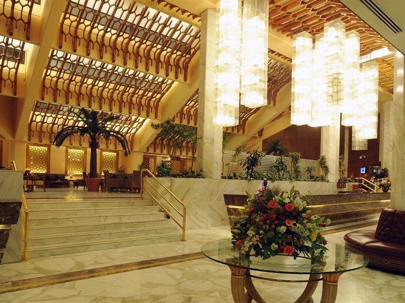 Makarem Ajyad Makkah Hotel Mecca Екстер'єр фото The photo shows a luxurious hotel lobby with elegant design features. It has high ceilings adorned with wooden beams and large, decorative light fixtures hanging from above. The lobby is brightly lit, creating a warm and inviting atmosphere. There ar